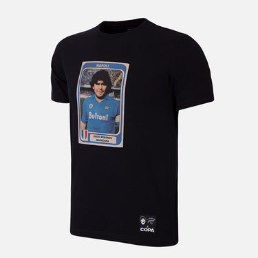 Flat-lay of the Maradona x COPA Napoli Football Sticker T-Shirt, featuring a black base with a large graphic print of a vintage Maradona Panini sticker.