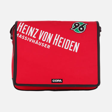 Flat-lay of the red Recycled Courier Bag featuring "HEINZ VON HEIDEN" text and the Hannover 96 badge.