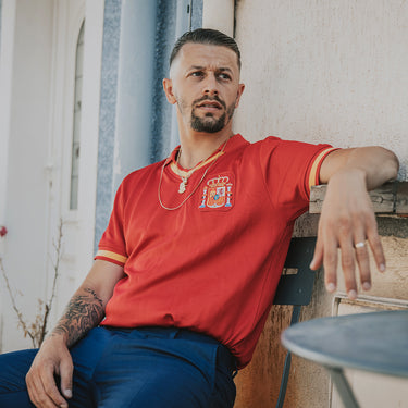 Model sitting on a bench wearing the Spain 1988 Retro Football Shirt, looking away from the camera.