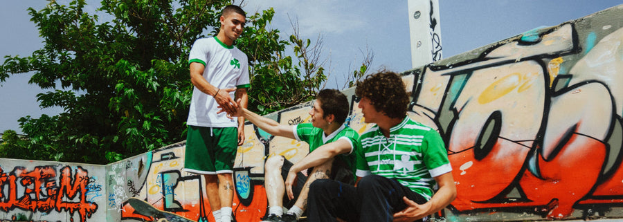 Three individuals in the Panathinaikos collection shaking hands in front of a graffiti-covered wall.