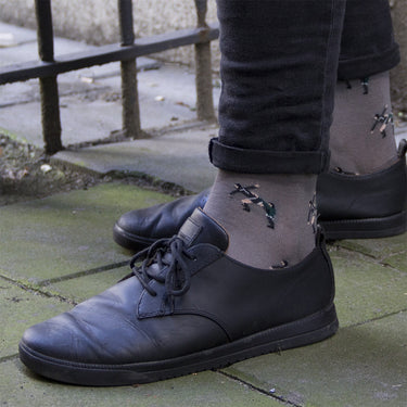 model wearing casual grey socks with a repeating pixel-style illustration of eric cantona football moment kung fu 