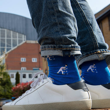model wearing casual blue socks with a repeating pixel-style illustration of zinedine zidane headbutt 2006