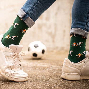 model wearing casual green socks with a repeating pixel-style illustration of a dutch iconic football moment at euro 1988