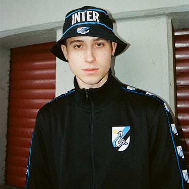 Model wearing the Inter bucket hat with a matching tracksuit in an urban setting