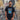 Model wearing the Maradona x COPA Napoli Football Sticker T-Shirt, standing in front of a mural featuring Diego Maradona.