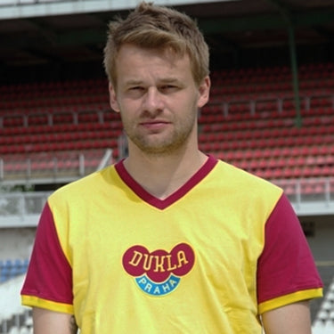Player wearing the Dukla Prague Away 1960's Retro Football Shirt, standing in a stadium setting.